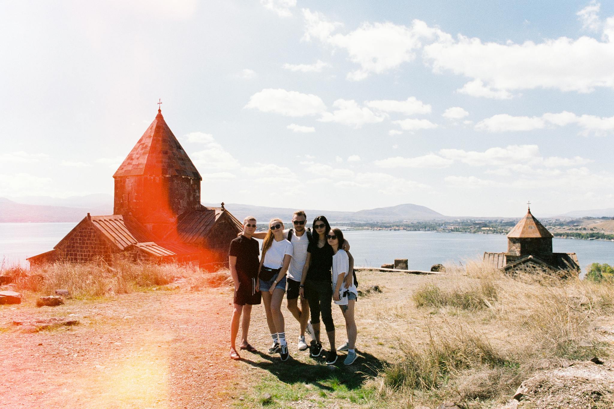 A group of friends enjoying a sunny day near an ancient monastery by the lake.
